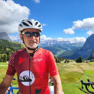 Herbert Lauble, Geschäftsleiter bei CasaVitale, an einem sonnigen Tag, mit seinem Fahrrad auf Radtour in den Alpen vor einer herrlich malerischen Berglandschaft.